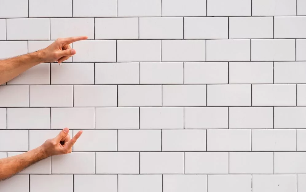 hand pointing white brick wall 23 2148296635 Por que essas tendências de banheiro irritam designers?