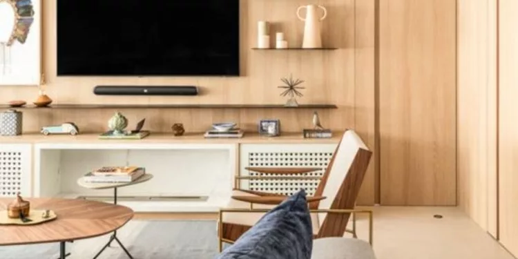 Na sala de estar desse apartamento, o arquiteto Bruno Moraes lançou mão da porta mimetizada para ocultar o acesso ao corredor que dá acesso à ala íntima. Discreta, ela assumiu também o papel de extensão do painel da TV | Projeto BMA Studio | Foto: Guilherme Pucci