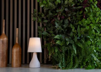 A parede verde é protagonista do estar e cria uma sensação de relaxamento. O painel e os adornos de madeira complementam a atmosfera natural juntamente com o abajur em cerâmica da Yamamura Collection / Projeto do escritório Degradê Arquitetura e foto de Emerson Rodrigues
