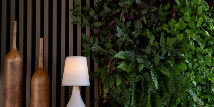 A parede verde é protagonista do estar e cria uma sensação de relaxamento. O painel e os adornos de madeira complementam a atmosfera natural juntamente com o abajur em cerâmica da Yamamura Collection / Projeto do escritório Degradê Arquitetura e foto de Emerson Rodrigues