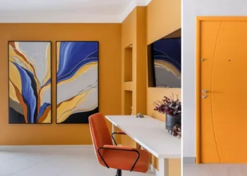 No apartamento localizado no Guarujá, a arquiteta Cristiane Schiavoni inspirou-se nos sentimentos  positivos que o mar proporciona para ousar nas cores. Na porta de entrada, a face interna exibe o amarelo e é ladeada por uma obra de arte. No dormitório, o laranja queimado também se sintoniza com a dupla de quadros.  O resultado é imóvel com identidade visual forte, onde o conforto sensorial e a estética caminham juntos |  Projeto Cristiane Schiavoni | Fotos: Rafael Renzo
