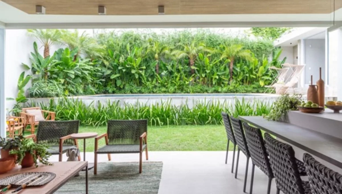Projeto prioriza a integração entre as áreas internas e externas para promover o relaxamento e a conexão com a natureza dos moradores e visitantes. Da varanda gourmet, moradores e visitantes desfrutam do verde com a seleção de espécies realizada pelo paisagista Luciano Zanardo | Projeto de arquitetura: Isabella Nalon | Foto: Julia Herman Fotografia
