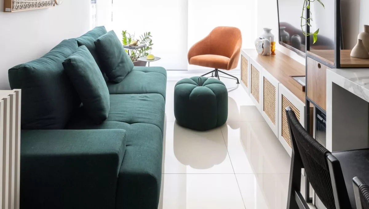 O sofá verde assumiu o papel de protagonista neste apartamento de 62 m² assinado pela arquiteta Elisa Maretti. Para que o verde não sobrecarregasse no ambiente, ela apostou na base neutra do projeto para balancear a presença da peça na área social integrada | Foto: Manuel Sá