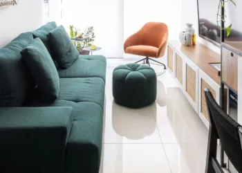 O sofá verde assumiu o papel de protagonista neste apartamento de 62 m² assinado pela arquiteta Elisa Maretti. Para que o verde não sobrecarregasse no ambiente, ela apostou na base neutra do projeto para balancear a presença da peça na área social integrada | Foto: Manuel Sá