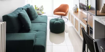 O sofá verde assumiu o papel de protagonista neste apartamento de 62 m² assinado pela arquiteta Elisa Maretti. Para que o verde não sobrecarregasse no ambiente, ela apostou na base neutra do projeto para balancear a presença da peça na área social integrada | Foto: Manuel Sá