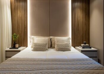 Neste projeto, a cabeceira estofada que se estende até o teto confere sofisticação e sensação de amplitude. As laterais com painel ripado, combinadas à iluminação indireta em LED, criam um ambiente intimista / Projeto de VilaVille Arquitetura e foto de JP Image