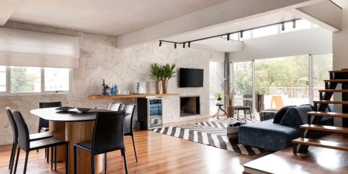 O apartamento com abundante luz natural ganhou uma parede revestida com granito rústico combinada com o aconchego do piso de madeira | Projeto: Daniela Funari Arquitetura | FOTO: Julia Novoa Fotografia