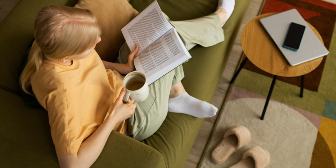 Uma tarde tranquila de leitura em um sofá verde musgo, com xícara de chá nas mãos e meias confortáveis: esse é o retrato perfeito de um cantinho da leitura acolhedor, onde o tempo desacelera.