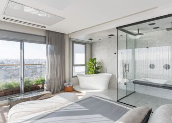 Um dos pedidos do morador para a Spaço Interior foi aproveitar o skyline de São Paulo não só na área social como na suíte master. Assim, integrado ao quarto, com vista para a Ponte Estaiada, está a sala de banho com banheira de imersão, box translucido, duchas duplas e até banco – tudo pensado para trazer os benefícios terapêuticos de uma sauna | Foto: Kadu Lopes