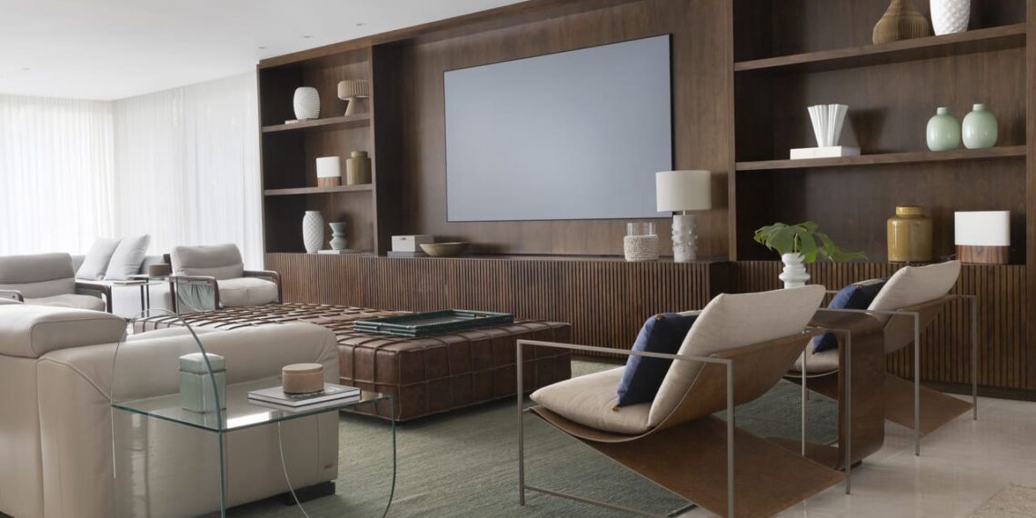 A estante foi o ponto de destaque do living com TV assinado pelo escritório Frezza & Figueiredo Arquitetura e Interiores. O projeto equilibra a tonalidade escura com uma paleta suave, neutra e aconchegante | Foto: Carolina Mossin