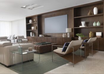 A estante foi o ponto de destaque do living com TV assinado pelo escritório Frezza & Figueiredo Arquitetura e Interiores. O projeto equilibra a tonalidade escura com uma paleta suave, neutra e aconchegante | Foto: Carolina Mossin