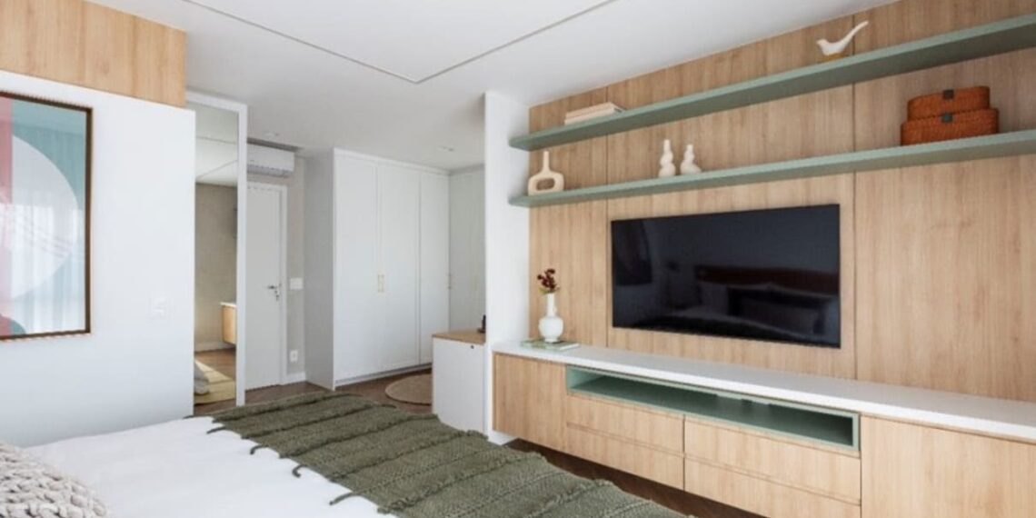 A parede em frente à cama pode seguir diversas linhas decorativas, recebendo pinturas, revestimentos ou painéis de marcenaria. O cuidado está em combinar o material e não competir com a TV | Projeto: Mari Milani | Foto: Mariana Camargo