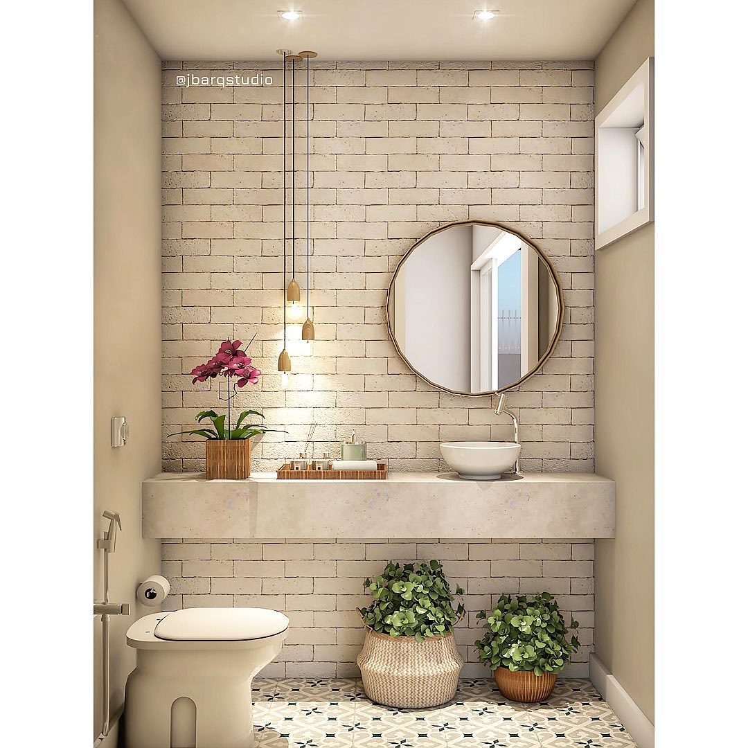 Lavabo rústico moderno com parede de tijolinhos claros, luminárias pendentes douradas, bancada de concreto aparente, cuba branca redonda e plantas em cestos de fibra natural.