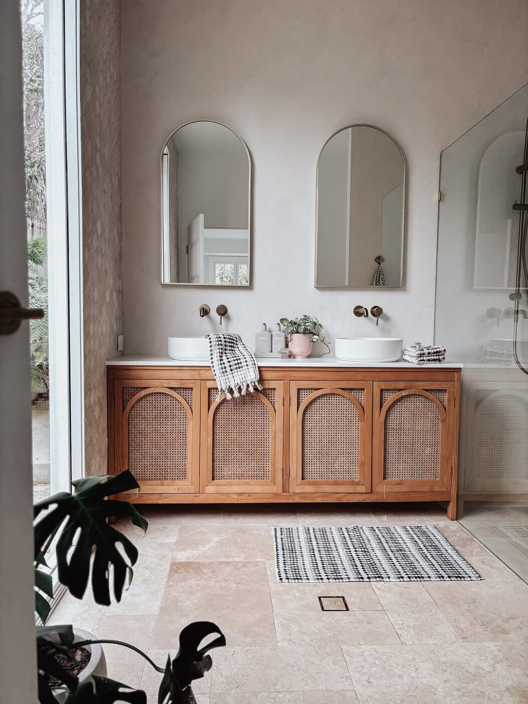 Banheiro com tile drenching em tons neutros, combinado a bancada de madeira e design acolhedor