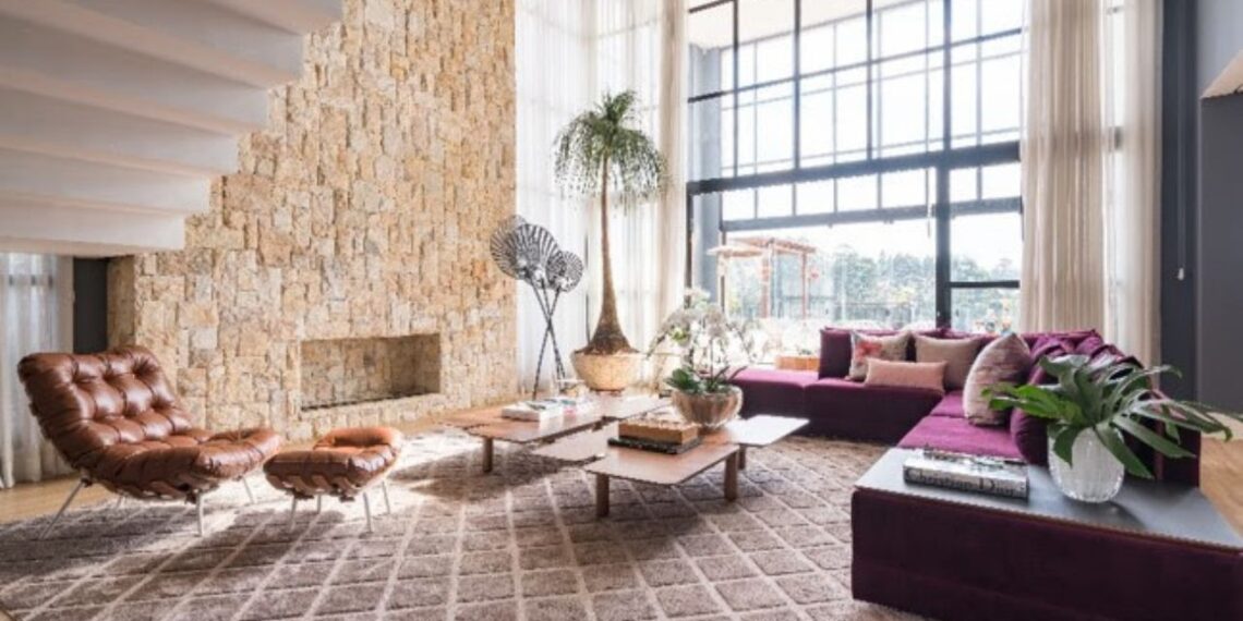 O esplendor e requinte do pé-direito duplo nos remete a história da arquitetura, onde as colunas e palácios possuíam pés muito amplos e buscavam conectar as pessoas com o etéreo. No projeto executado pela arquiteta Ana Rozenblit, do escritório Spaço Interior, a arquitetura do living explora os amplos janelões de vidro e a beleza da parede revestida em pedra | Foto: Kadu Lopes