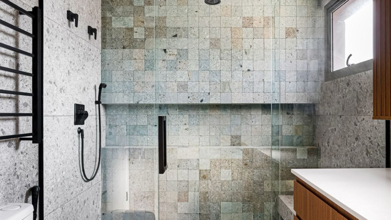 Banheiro com revestimento em pedra natural com tons esverdeados, criando efeito spa na decoração.