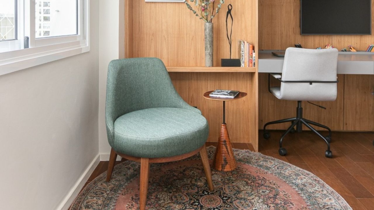 Poltrona verde em escritório com painel de madeira, exemplo de uso discreto do verde na decoração.