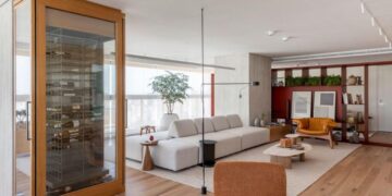 Batizado de ‘Apartamento Ripas’, o projeto do arquiteto Raphael Wittmann exibe uma área de estar grandiosa que reflete a identidade dos moradores. Uma adega entrega imponência logo na entrada e possui duas portas que servem ao estar e à sala de jantar | Projeto Rawi Arquitetura + Design | Foto: Rafael Renzo