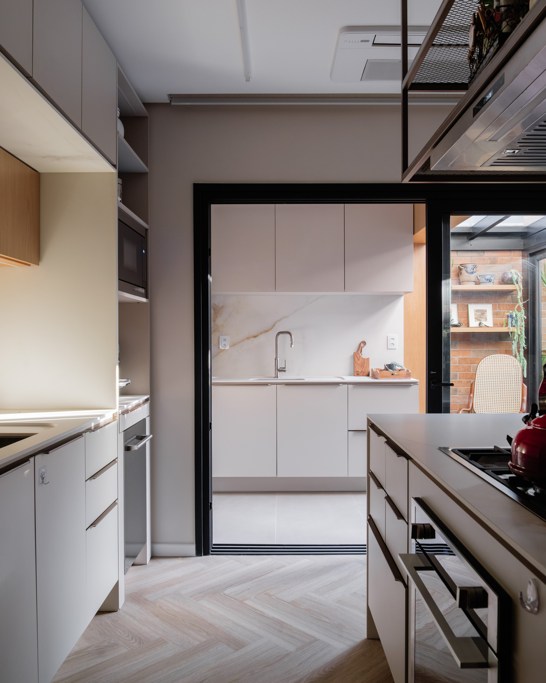 Cozinha clara com piso espinha de peixe e abertura ampla para área verde.