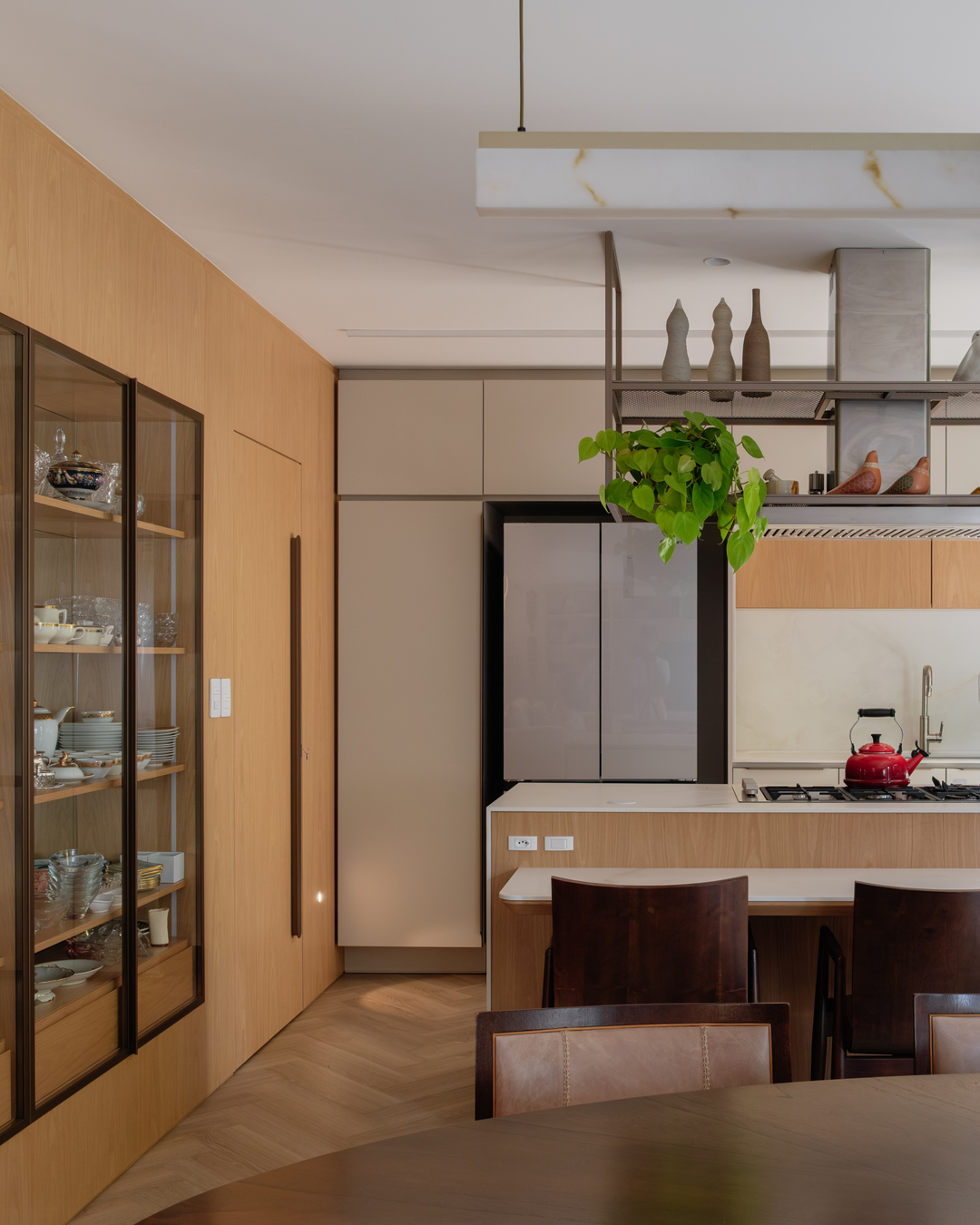 Cozinha integrada com ilha central, marcenaria amadeirada e bancada clara.