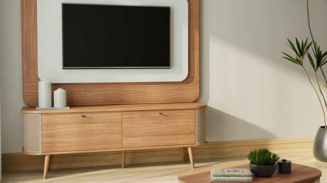 Rack pé palito em madeira com nicho para discos de vinil, TV na parede e poltronas verde e mostarda em sala clara.