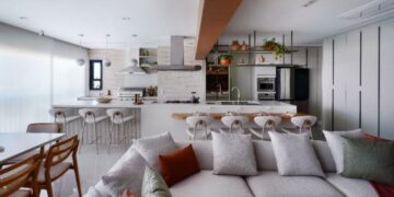 A conexão entre a cozinha e o gourmet pode ser executada de diversas maneiras, inclusive como protagonistas da área social do imóvel, assim como a arquiteta Rosangela Pena executou no projeto do apartamento acima. Nos dias de eventos, a cozinha é o apoio para complementar os pratos que acompanharão o churrasco | FOTO: Sidney Doll