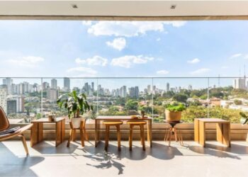 Ao invés de ambientes feitos apenas para impressionar, muitos moradores estão à procura do acolhimento à sua maneira. Na varanda deste apartamento, o arquiteto Bruno Moraes posicionou bancos e mesas produzidos a partir da madeira reaproveitada da escada do apartamento, dando uma nova vida a um material que antes seria descartado | Projeto BMA Studio | Foto: Guilherme Pucci