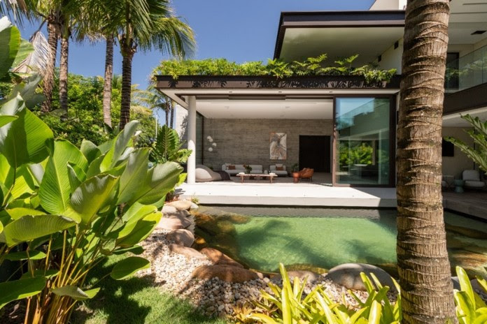 Lago na área externa protagoniza projeto residencial que une paisagismo com arquitetura moderna