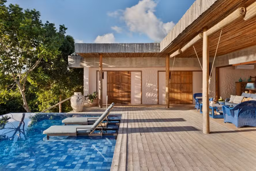 Casa Berimbau, na Bahia, se fecha para a rua e se abre para uma piscina que parece estar dentro e fora da sala ao mesmo tempo
