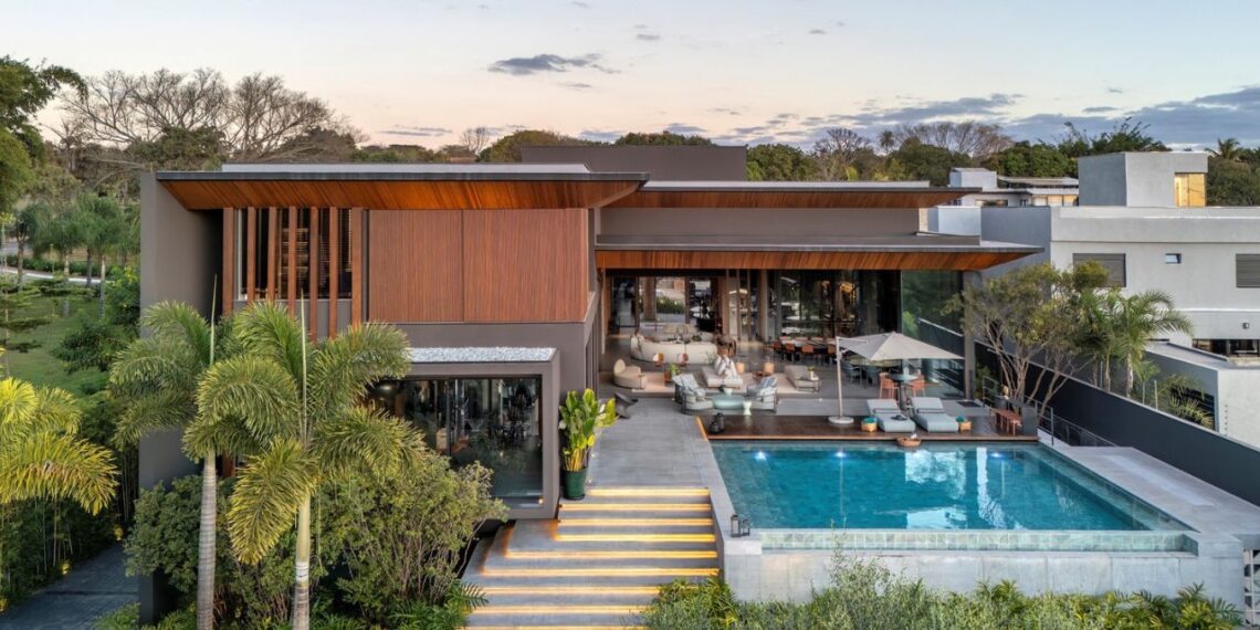 Com uma área de convivência conectada a espaços externos, o verde parece se fundir à arquitetura. O entorno da casa contém espécies como palmeira-rabo-de-raposa, jabuticabeira, imbê e pau-brasil | Paisagismo de Depieri Paisagismo, arquitetura de Denise Zuba Arquitetos, construção de Centra Engenharia e foto de Edgar Cesar