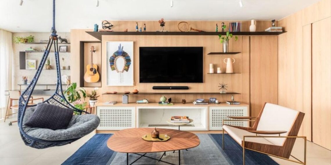 Com desenho orgânico e acabamento em madeira, a mesa de centro selecionada pelo arquiteto Bruno Moraes introduz leveza às linhas retas presentes na sala de estar | Projeto BMA Studio | Foto: Guilherme Pucci