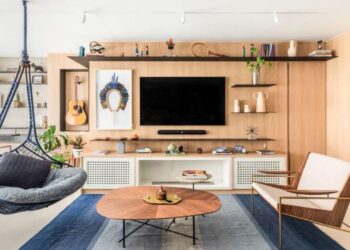 Com desenho orgânico e acabamento em madeira, a mesa de centro selecionada pelo arquiteto Bruno Moraes introduz leveza às linhas retas presentes na sala de estar | Projeto BMA Studio | Foto: Guilherme Pucci